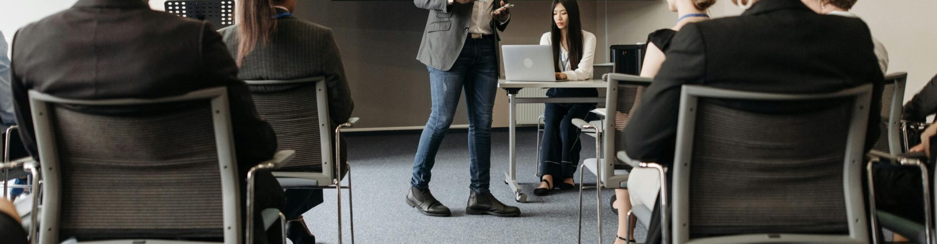 Diverse group attending a business seminar with a presenter and screen display.